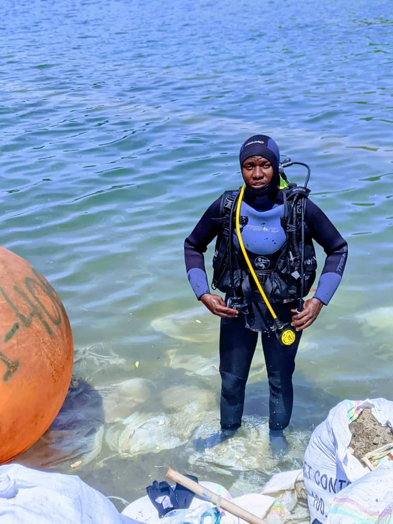 Diver preparing gear on boat with green hills behind